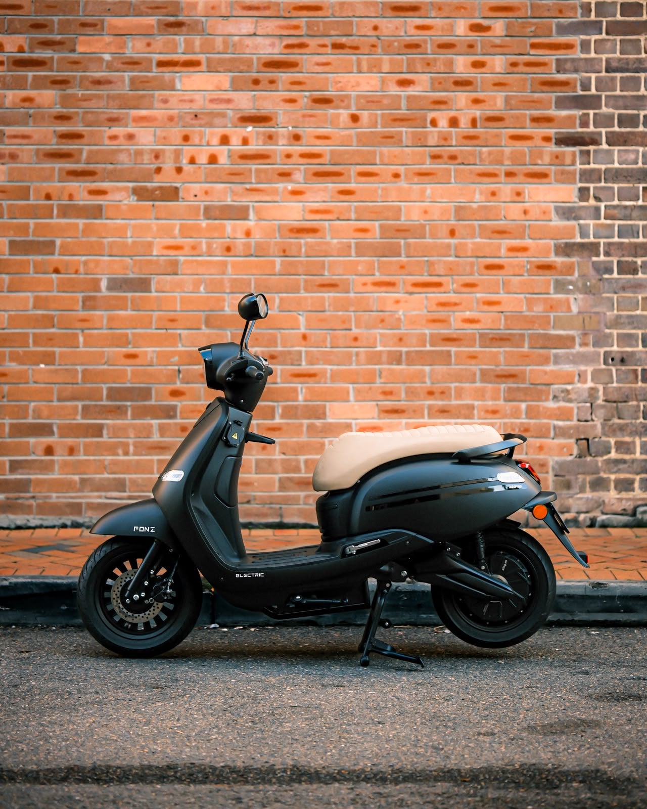 FONZ Arthur electric scooter parked against a brick wall