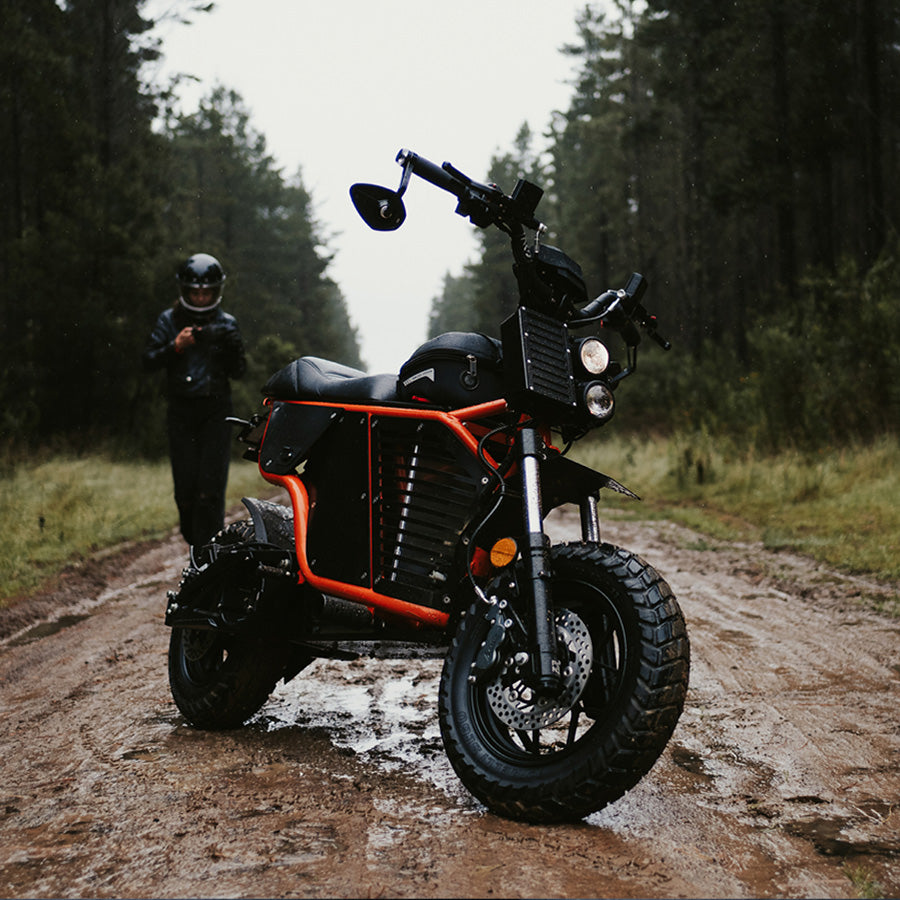 FONZ NKD electric motorbike with bar-end mirrors on a muddy forest trail